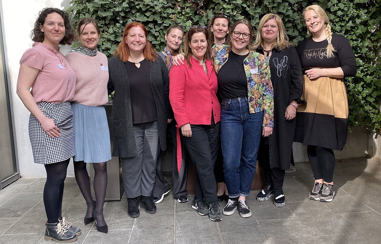  9 persons standing in a line smiling for a group photo.