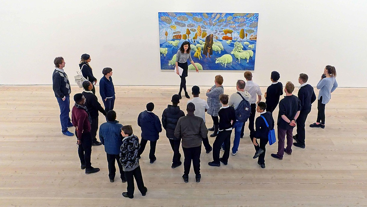 © Jeffrey Blackler / Alamy Stock Foto A group of people stand in front of a modern painting together with a museum educator. The image is photographed from bird perspective.