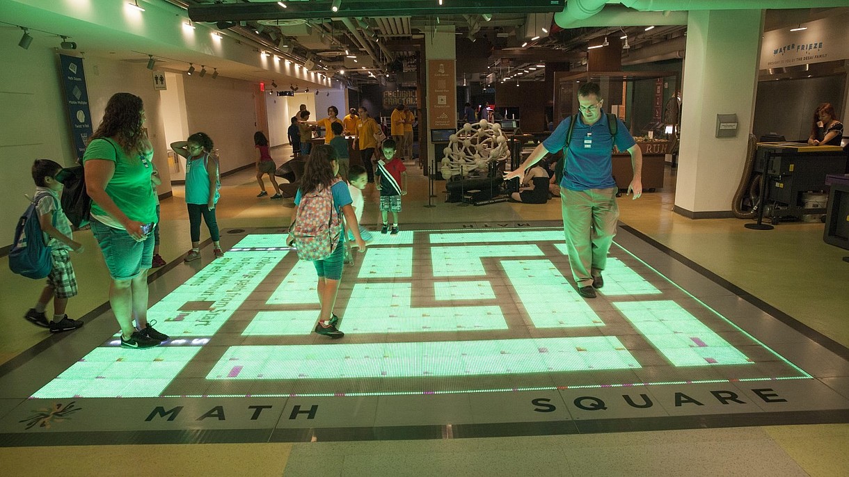 © David Grossman / Alamy Stock Foto A group of children and adults interact with a digital projection on the floor.