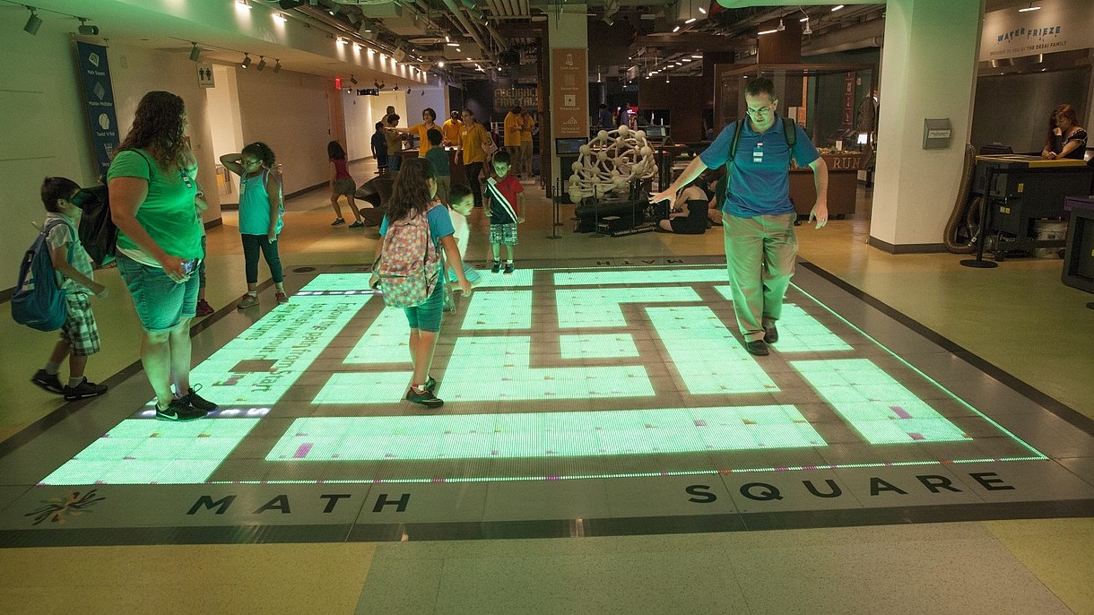 © David Grossman / Alamy Stock Foto A group of children and adults interact with a digital projection on the floor.