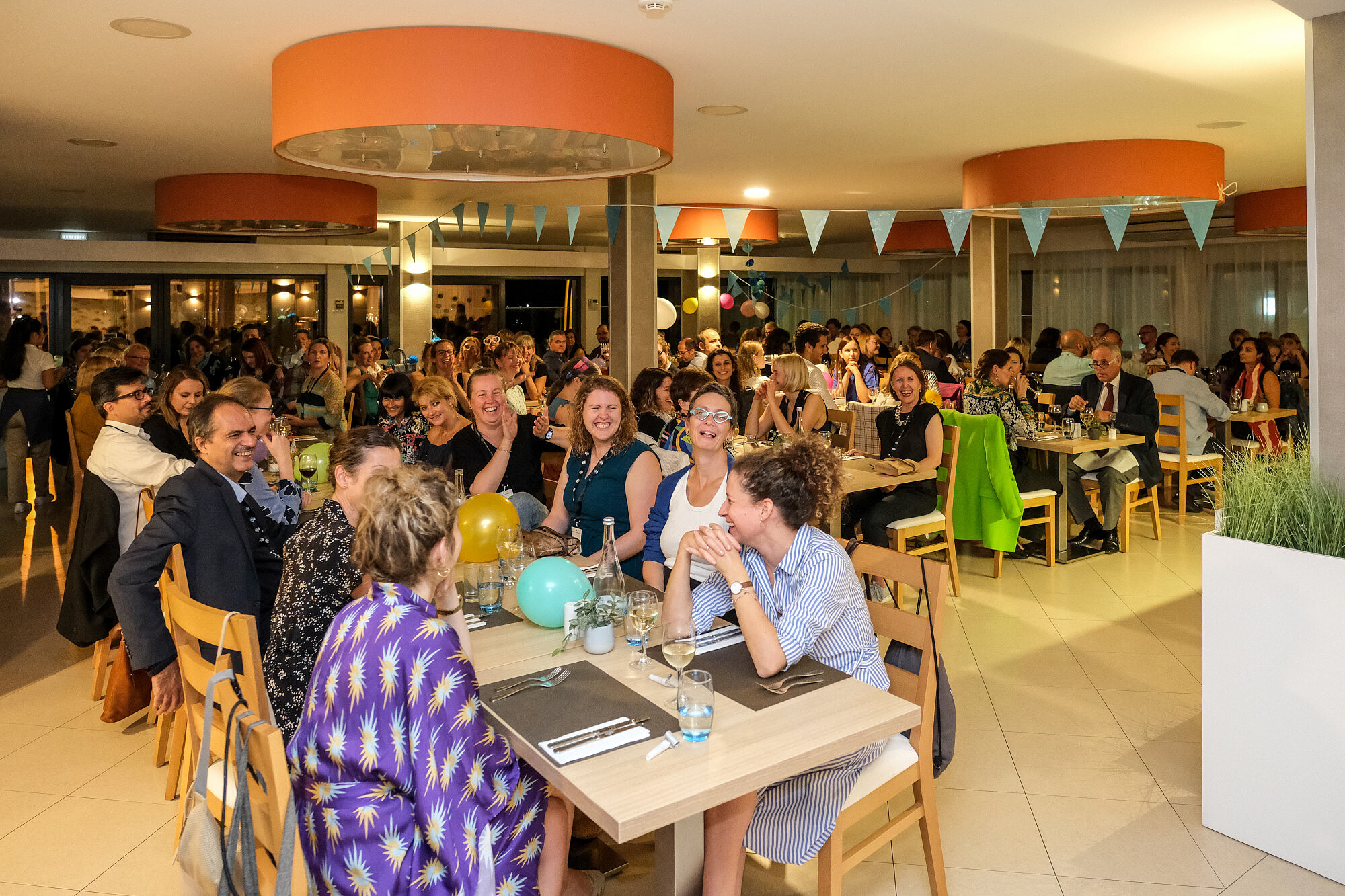 Various people sit at restaurant tables. They are talking and laughing.  © Image: Jorge Gomes