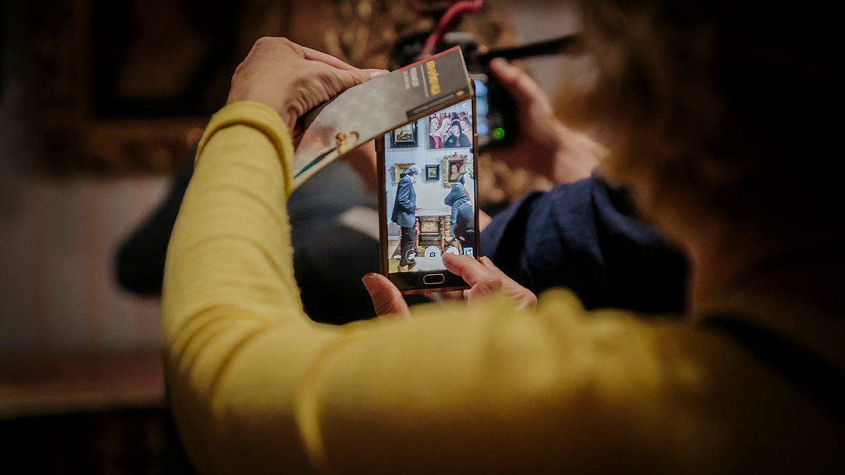  A person is taking a photo of the exhibition display with their smartphone