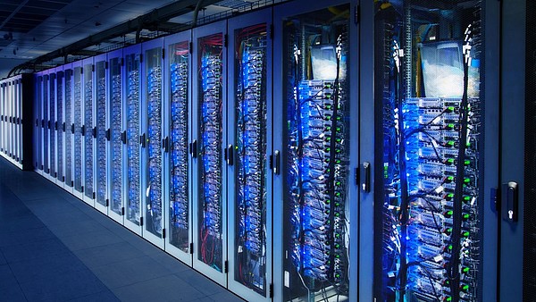 A row of cabinets is filled with server racks in a data center.