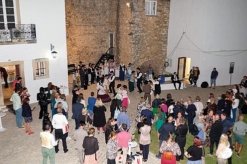 A group in traditional clothing is performing a dance in a historic courtyard. An audience is watching them.  © Image: Jorge Gomes