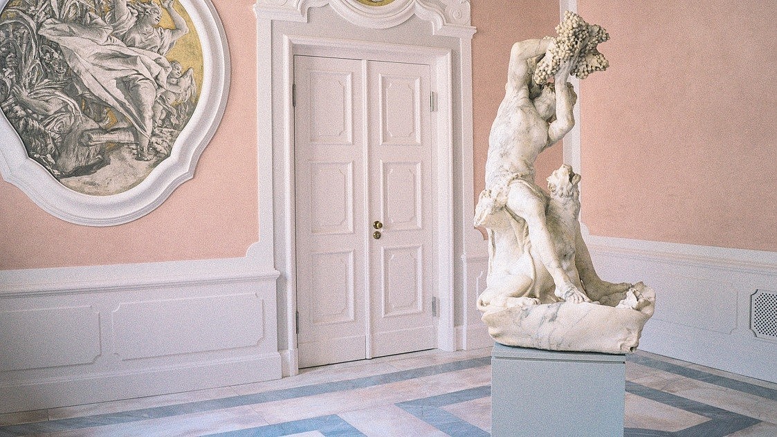  Classical stone sculpture shown inside a light and empty exhibition space.