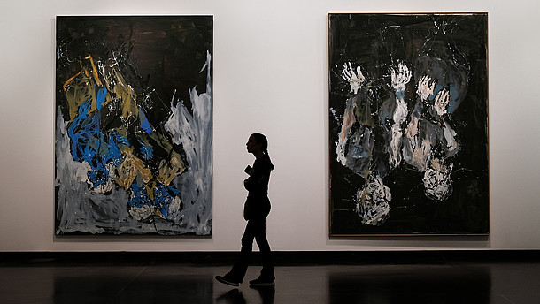  Between two hugs paintings is the silhouette of a person walking exactly between them.   