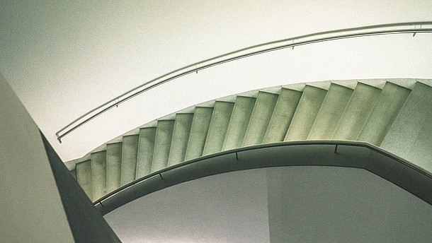  Abstract view of a modern stairwell from above. To the right a person is shown walking out of the picture frame.