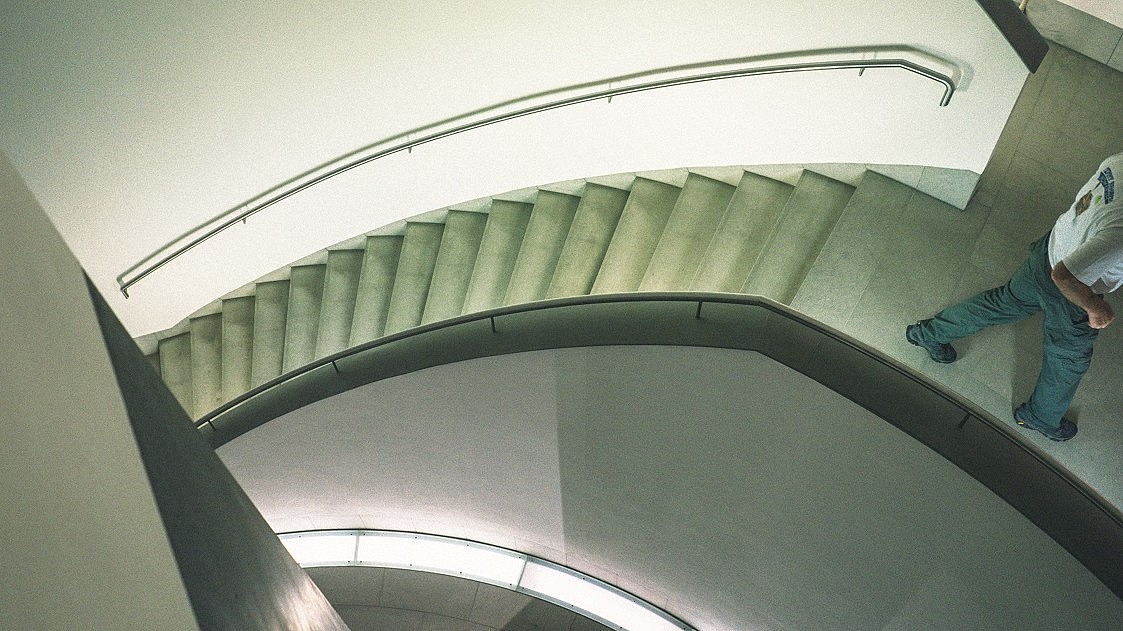  Abstract view of a modern stairwell from above. To the right a person is shown walking out of the picture frame.