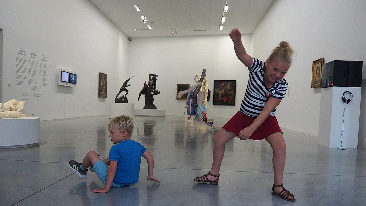  Two children are depicted dancing joyfully inside an exhibition space.