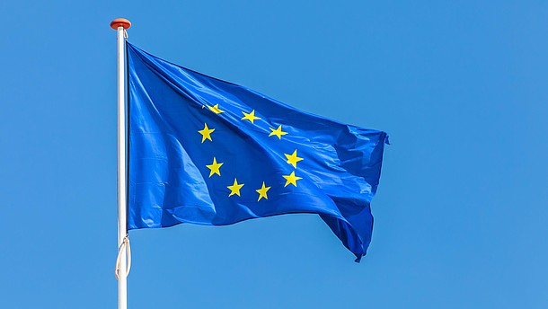  The European flag waving in front of a clear blue sky.