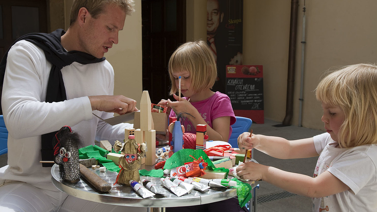 © Image: Jan Pohribny QEP, Czech Association of Museums and Galleries A man helps two children build paper dolls. 
