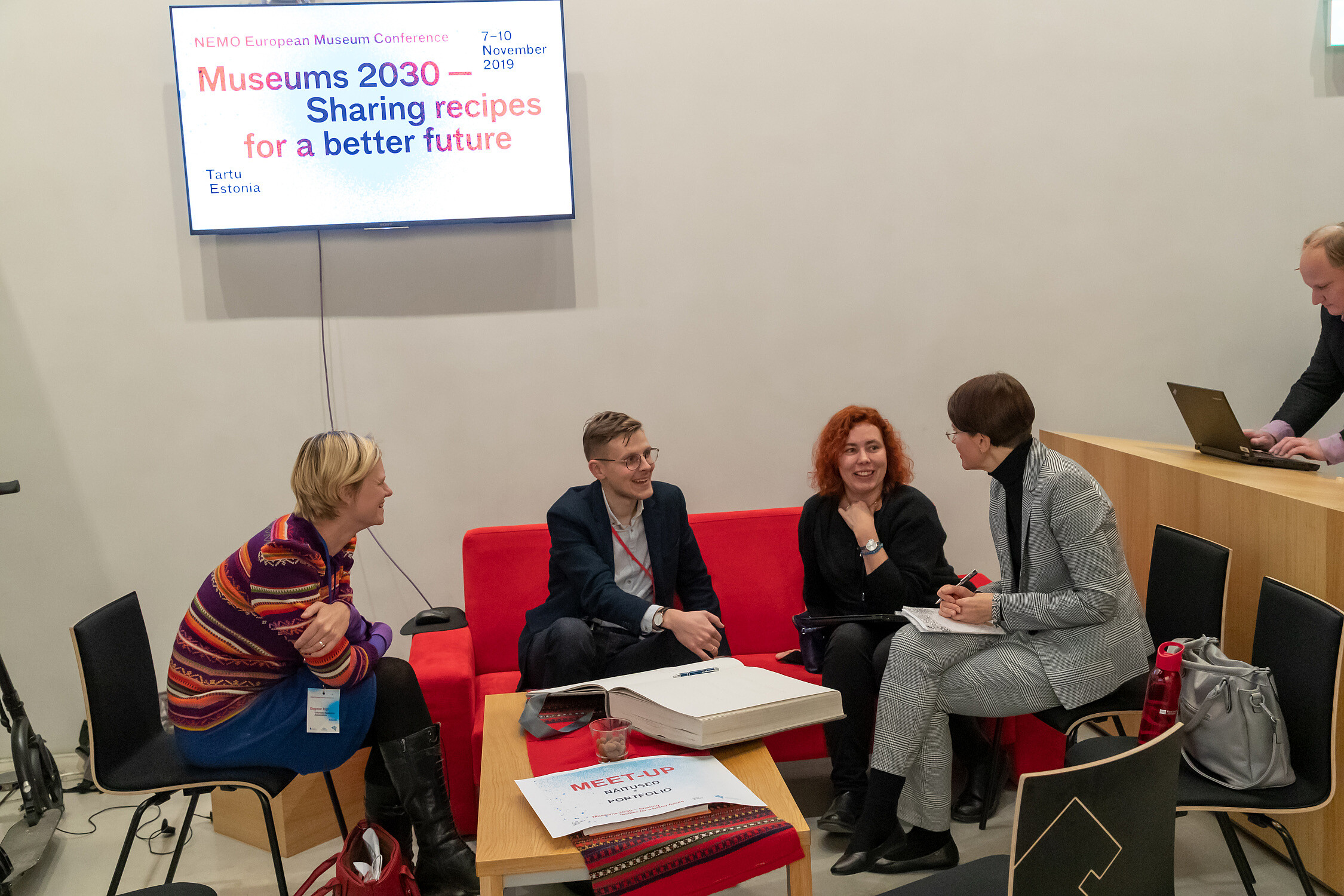 Four people sitting down are discussing something and smiling.   © Image: Arp Karm